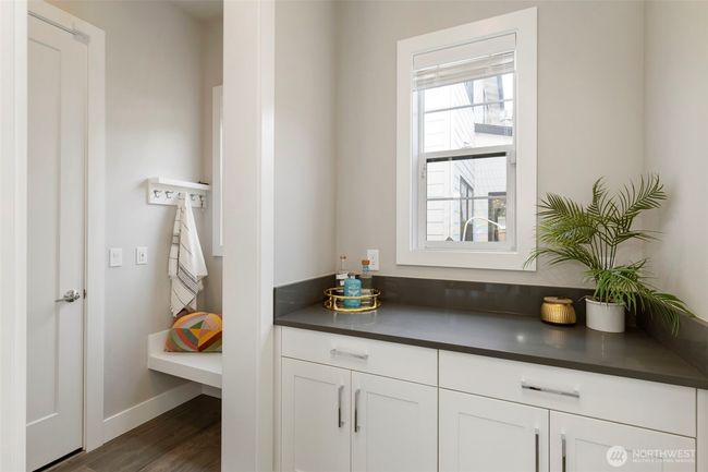 This stylish and functional drop zone connects the garage to the kitchen, offering built-in cabinetry, counter space, and a cozy bench with hooks for effortless organization. It's the perfect landing spot for bags, coats, and daily essentials—keeping clutter out of sight and convenience within reach. | Image 18