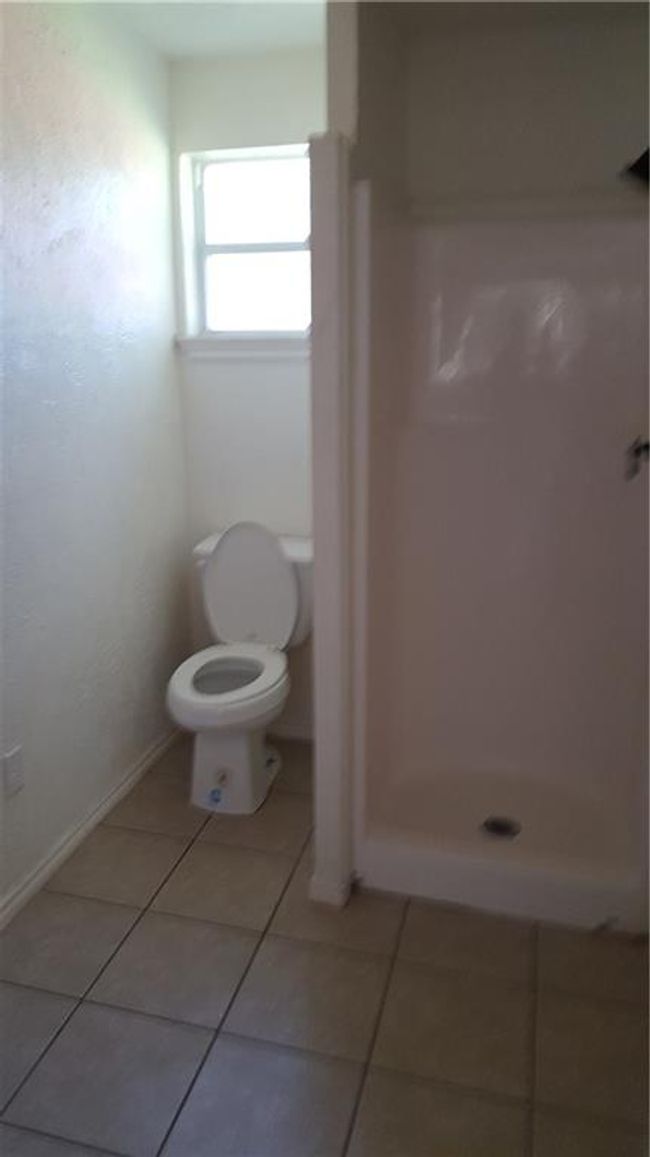 Bathroom with tile patterned flooring, a stall shower, and toilet | Image 6