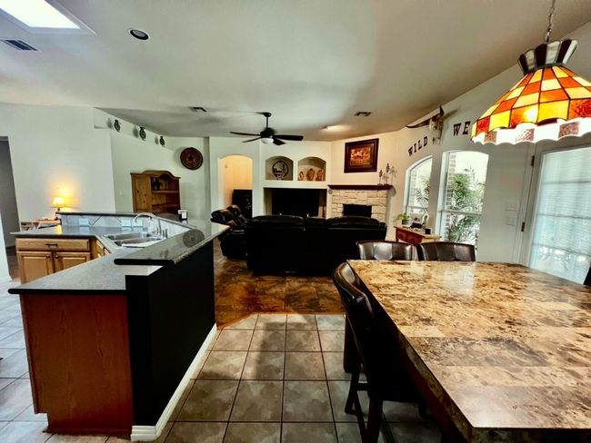 Kitchen featuring a spacious island, ceiling fan, dark tile patterned floors, built in shelves, and vaulted ceiling | Image 8