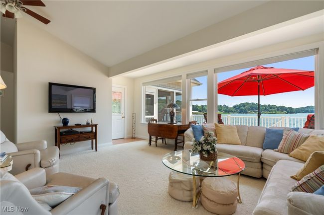 Carpeted living area featuring ceiling fan and lofted ceiling | Image 7