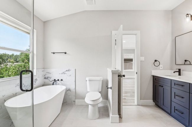Full bath featuring vanity, a freestanding bath, vaulted ceiling, toilet, and tile patterned floors | Image 24