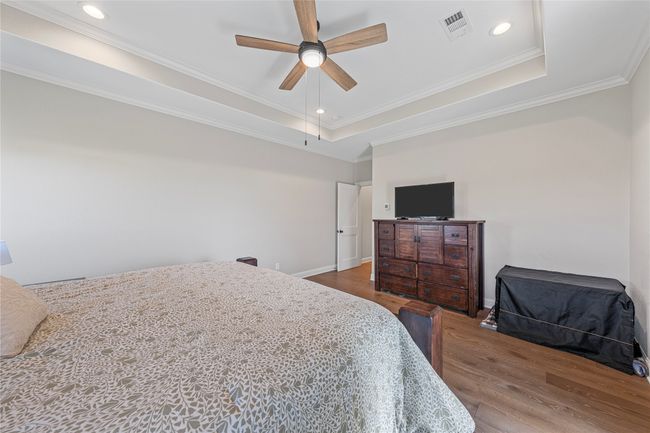 Bedroom featuring crown molding, visible vents, a tray ceiling, and wood finished floors | Image 23