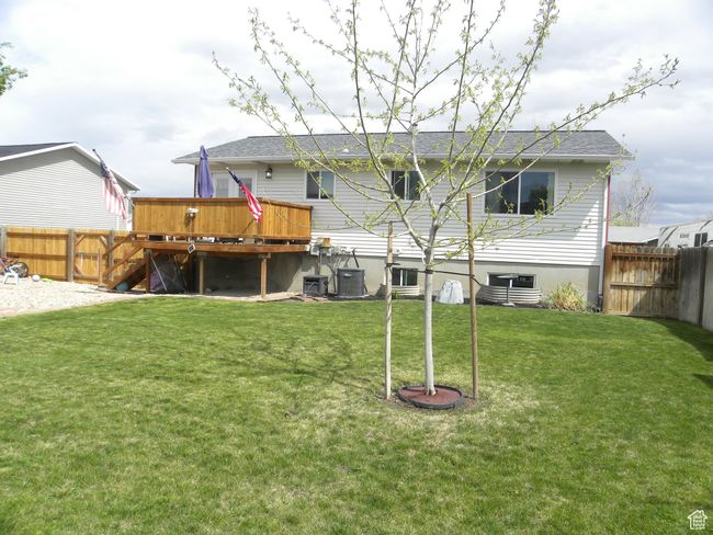 Back of house with a deck, a fenced backyard, central air condition unit, and a lawn | Image 34