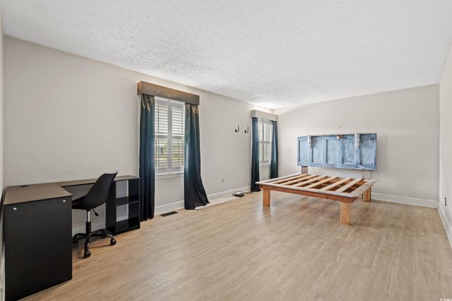 Interior space featuring a textured ceiling, light wood-style floors, visible vents, and baseboards | Image 18