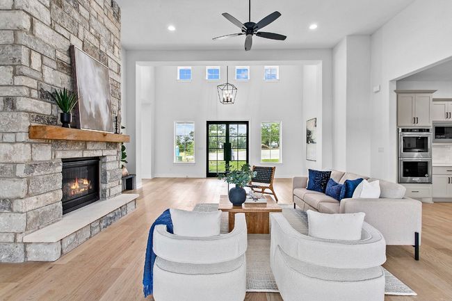 Living room featuring a fireplace, light wood finished floors, ceiling fan, recessed lighting, and a high ceiling | Image 5