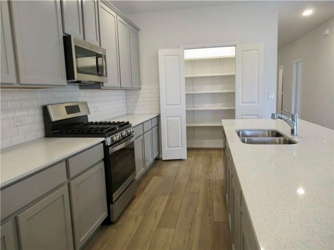 Kitchen with appliances with stainless steel finishes, gray cabinetry, light wood-style flooring, backsplash, and recessed lighting | Image 5