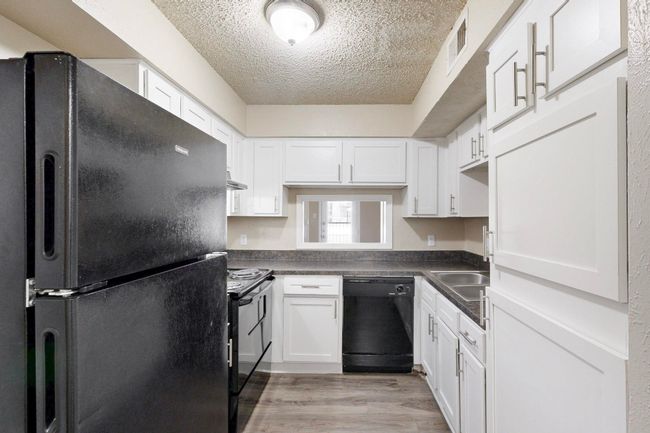 Kitchen with visible vents, black appliances, a textured ceiling, dark countertops, and white cabinetry | Image 18