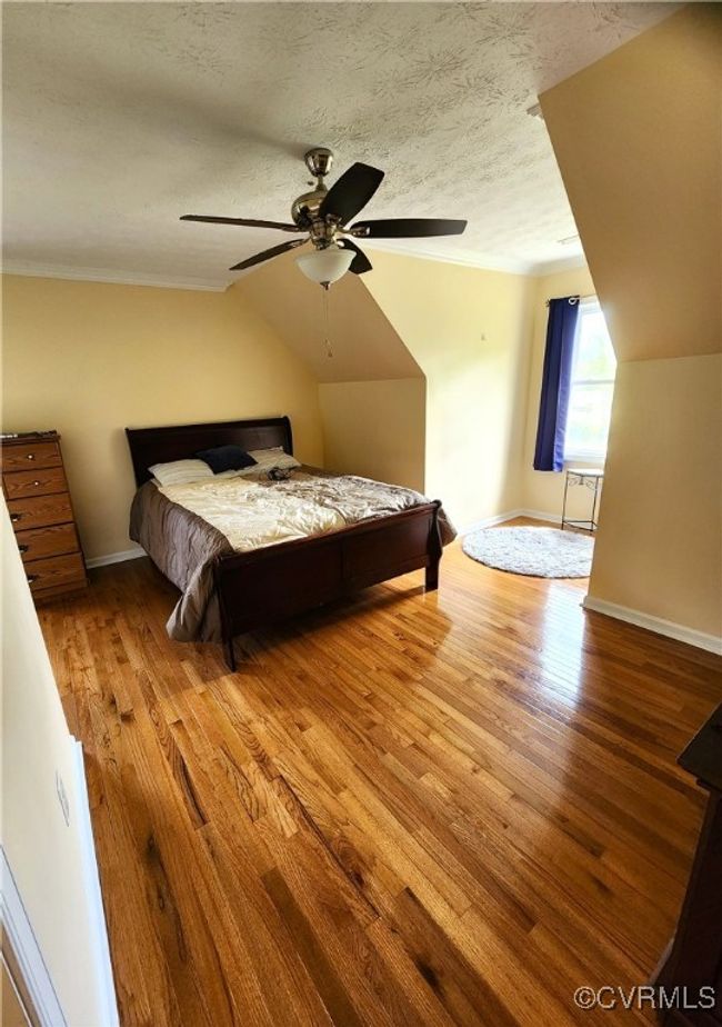 Bedroom with wood finished floors, lofted ceiling, a textured ceiling, crown molding, and a ceiling fan | Image 21