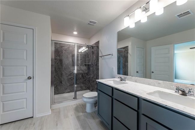 Bathroom featuring wood finished floors, a marble finish shower, and double vanity | Image 22