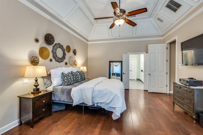Bedroom with coffered ceiling, dark wood-style floors, ornamental molding, baseboards, and a ceiling fan | Image 21