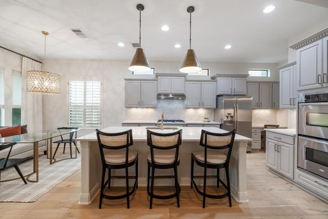 Remodeled Kitchen featuring gray cabinetry, stainless steel appliances, light countertops, under cabinet range hood, and a kitchen island with sink | Image 8
