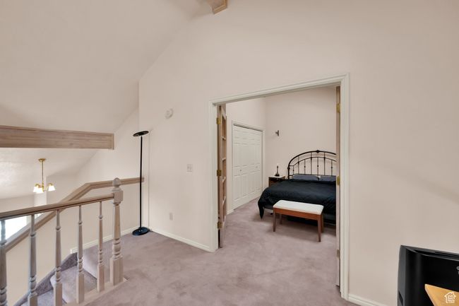 Corridor with an upstairs landing, light carpet, lofted ceiling with beams, baseboards, and an inviting chandelier | Image 14