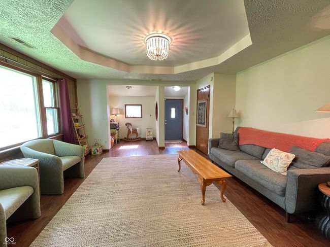 living area featuring a chandelier, wood finished floors, and a raised ceiling | Image 14