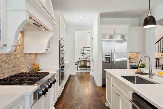 Kitchen with appliances with stainless steel finishes, recessed lighting, tasteful backsplash, light countertops, and arched walkways | Image 4