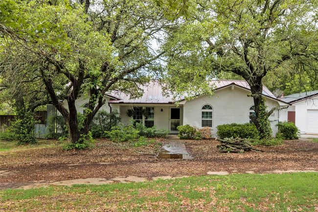 Ranch-style home with a garage, fence, metal roof, and brick siding | Image 4