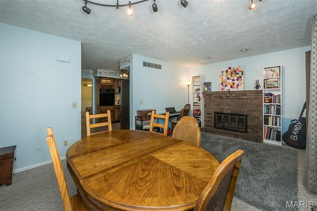 Carpeted dining space featuring a fireplace, baseboards, and a textured ceiling | Image 14