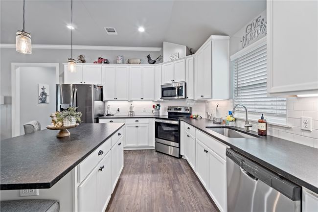 Kitchen featuring a sink, dark countertops, visible vents, and appliances with stainless steel finishes | Image 14