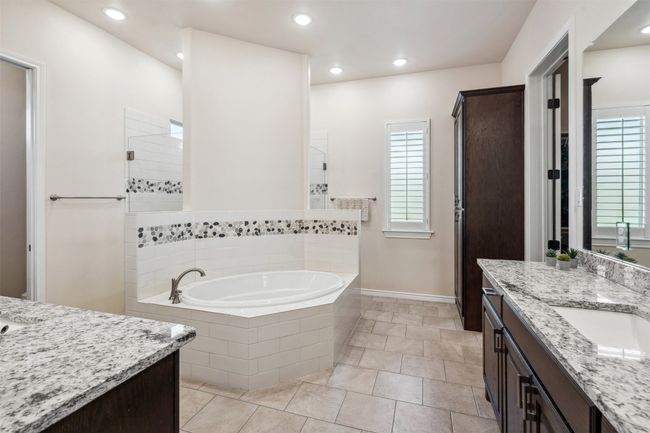 Bathroom featuring a sink, baseboards, two vanities, walk in shower, and a garden tub | Image 25