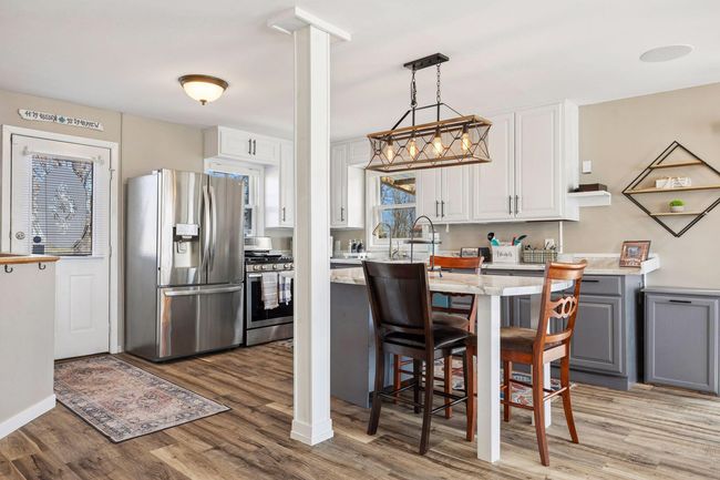 The kitchen features a spacious island with a stylish chandelier overhead, a double sink perfectly positioned under a window for natural light, and ample counter space. Stainless steel appliances complete the modern and functional design. | Image 5