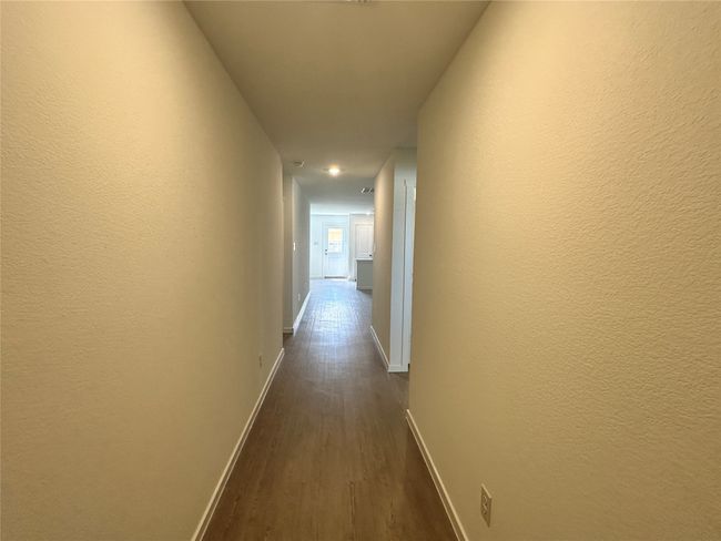 Hall with dark wood-style flooring and a textured wall | Image 11