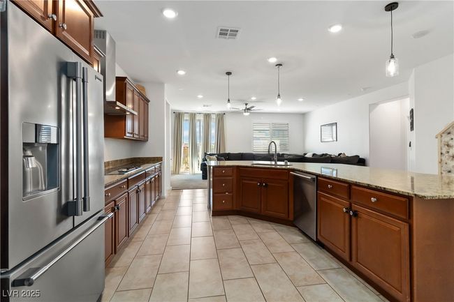 Kitchen featuring visible vents, appliances with stainless steel finishes, open floor plan, decorative light fixtures, and a sink | Image 18