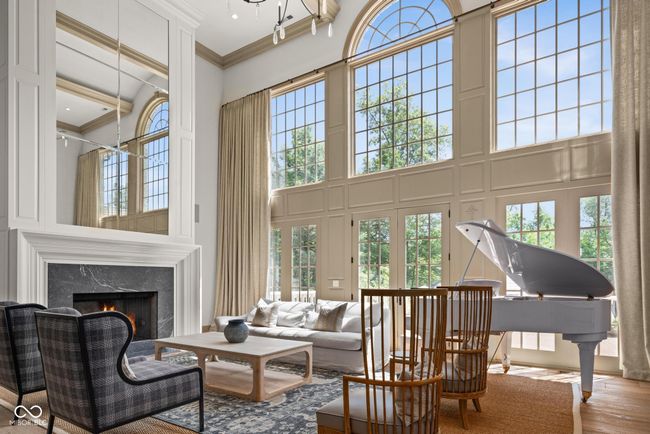 living room featuring a high ceiling, ornamental molding, a high end fireplace, and wood finished floors | Image 8