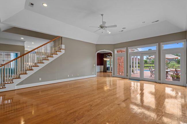 Unfurnished living room with a ceiling fan, wood finished floors, arched walkways, plenty of natural light, and recessed lighting | Image 9
