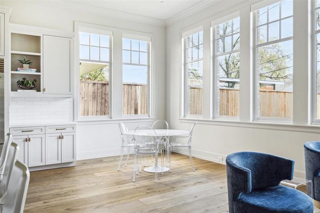 This thoughtfully designed kitchen extension offers ample space for a charming breakfast nook and a separate seating area. Surrounded by expansive windows, the space is bathed in natural light, creating an inviting setting for casual dining and relaxed gatherings. | Image 13