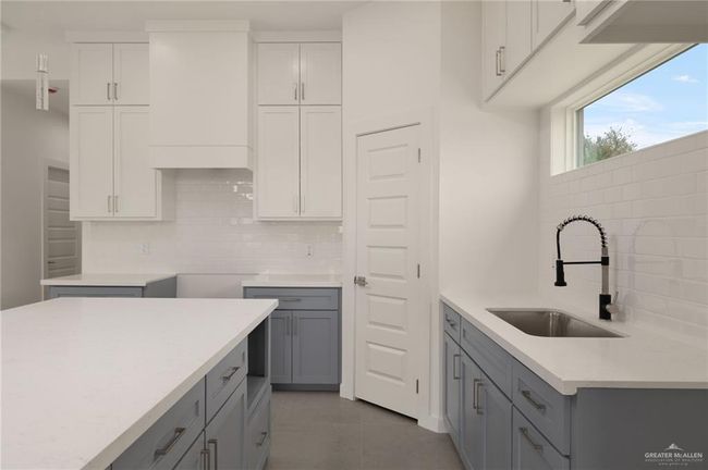 Kitchen with gray cabinets, tasteful backsplash, light countertops, and white cabinetry | Image 7