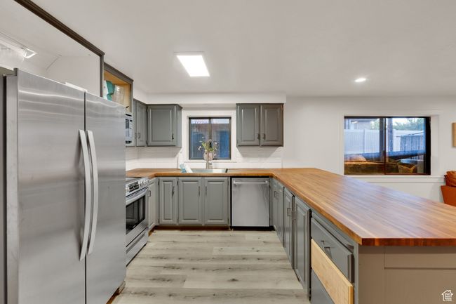 Kitchen featuring appliances with stainless steel finishes, wood counters, gray cabinetry, and recessed lighting | Image 27