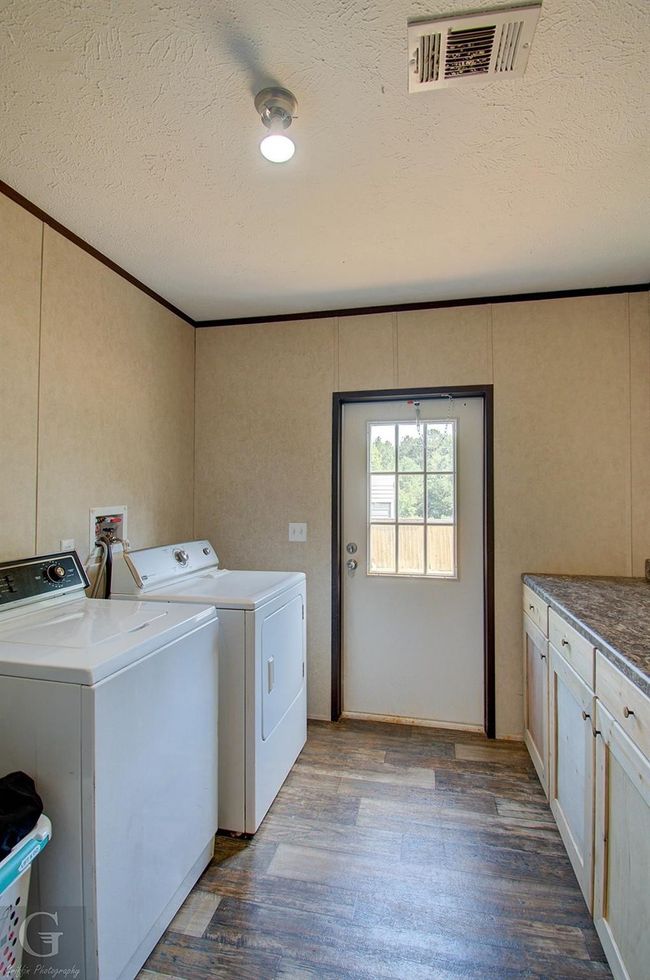 Laundry area featuring washer and clothes dryer, cabinet space, wood finished floors, a textured ceiling, and ornamental molding | Image 9