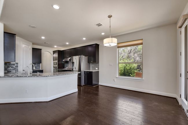 Kitchen with appliances with stainless steel finishes, backsplash, light stone countertops, dark wood-style flooring, and recessed lighting | Image 15