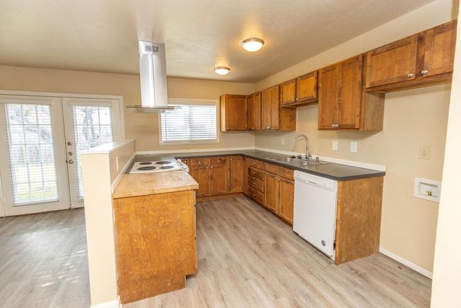 Kitchen with white appliances, french doors, ventilation hood, sink, and light hardwood / wood-style flooring | Image 7