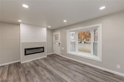 Living room with wood-type flooring and electric fireplace with shiplap. | Image 3