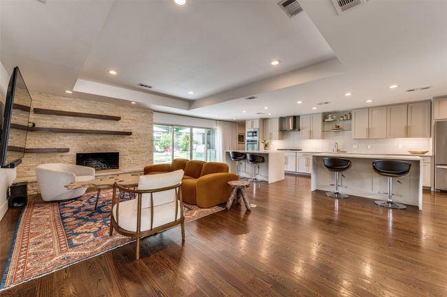 Living room featuring a raised ceiling, dark wood finished floors, a fireplace, and recessed lighting | Image 12