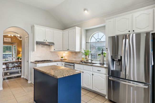 Kitchen featuring granite countertops, white cabinets, a sink, light tile patterned floors, and stainless steel appliances | Image 10