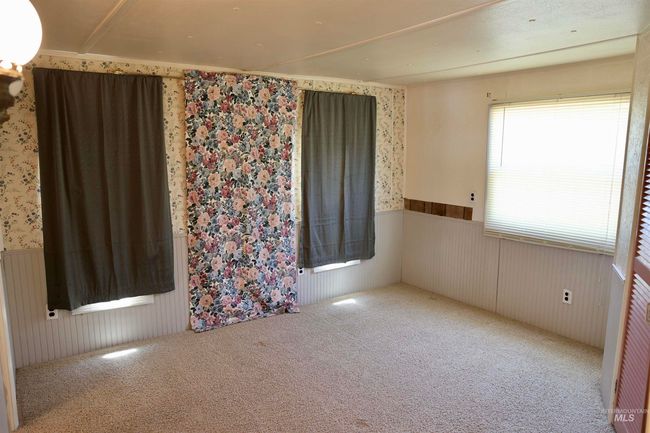 Empty room with wainscoting, wallpapered walls, and carpet flooring | Image 10