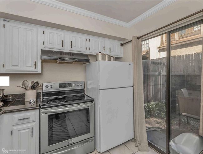 Kitchen with electric range, under cabinet range hood, white cabinetry, and freestanding refrigerator | Image 12