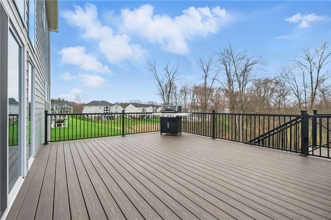 Expansive low-maintenance composite deck with sleek black railing, perfect for outdoor entertaining and relaxing. Overlooks a private, wooded backdrop and neighboring green space, offering both scenic views and a sense of privacy. Gas line to grill. | Image 18