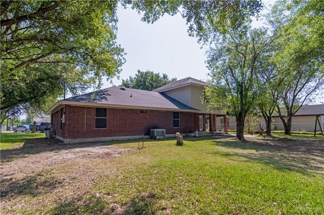 Rear view of house with cooling unit, a lawn, and brick siding | Image 18