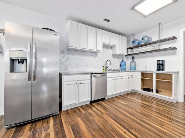 Kitchen with white cabinets, open shelves, appliances with stainless steel finishes, and dark wood finished floors | Image 9
