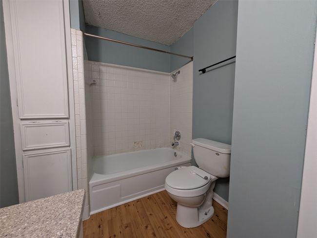 Bathroom with wood finished floors, a textured ceiling, shower combination, and toilet | Image 20