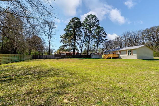 View of yard featuring an outbuilding, fence, a storage shed, and a wooden deck | Image 7