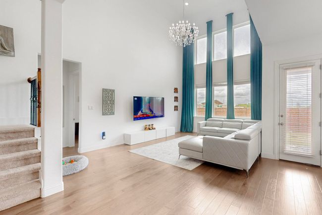 Living area with light wood-style floors, a high ceiling, an inviting chandelier, and stairs | Image 5