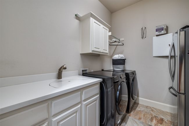The oversized laundry room offers abundant cabinetry for storage, a convenient sink, and space for an additional refrigerator—making everyday chores a breeze. | Image 23