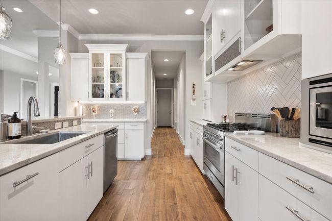 Kitchen with pendant lighting, white cabinetry, stainless steel appliances, and loads of counter space. | Image 11