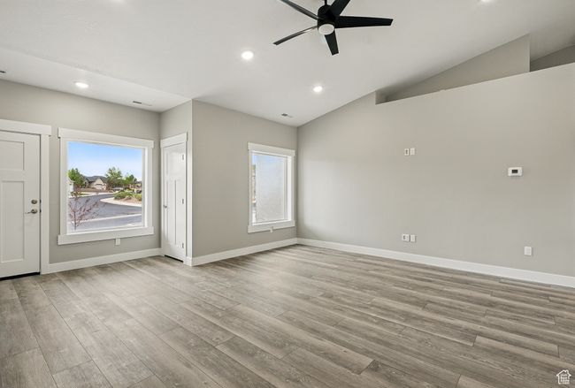 Unfurnished room featuring a ceiling fan, plenty of natural light, recessed lighting, wood finished floors, and lofted ceiling | Image 8