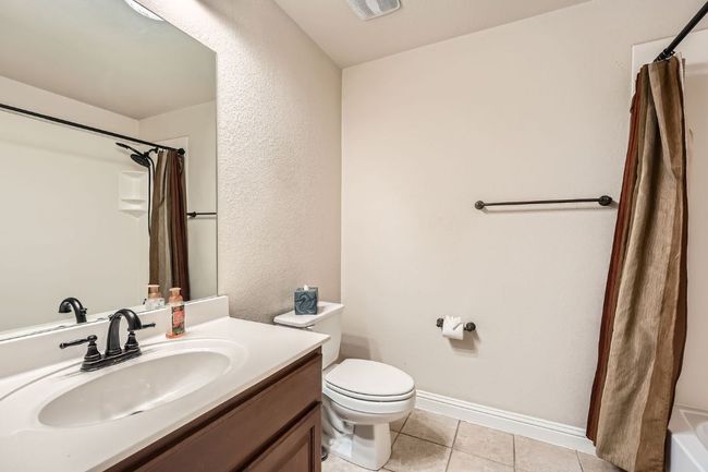 Bathroom featuring a shower with curtain, tile patterned floors, baseboards, vanity, and toilet | Image 30