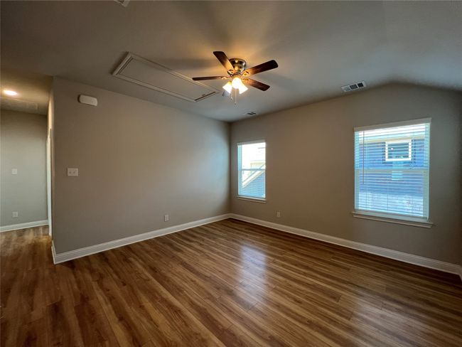 Unfurnished room featuring attic access, dark wood-type flooring, a ceiling fan, baseboards, and vaulted ceiling | Image 14
