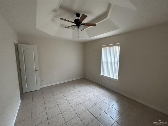 Unfurnished room featuring a tray ceiling, light tile patterned floors, ceiling fan, and baseboards | Image 4